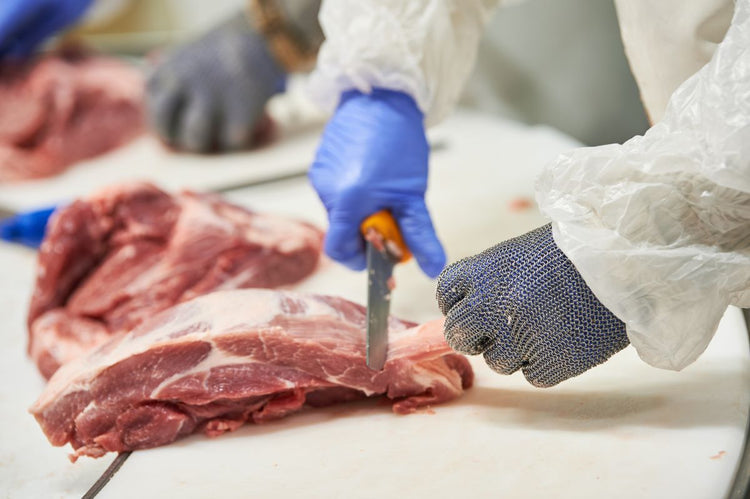 Factory worker slicing a steak in a meat processing facility