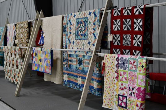 Quilts hanging on racks at a quilt show