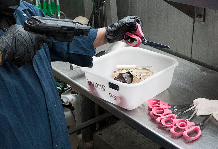 a worker scans poultry processing shears on a production line before use